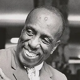 A black and white photo of Howard Thurman, smiling.
