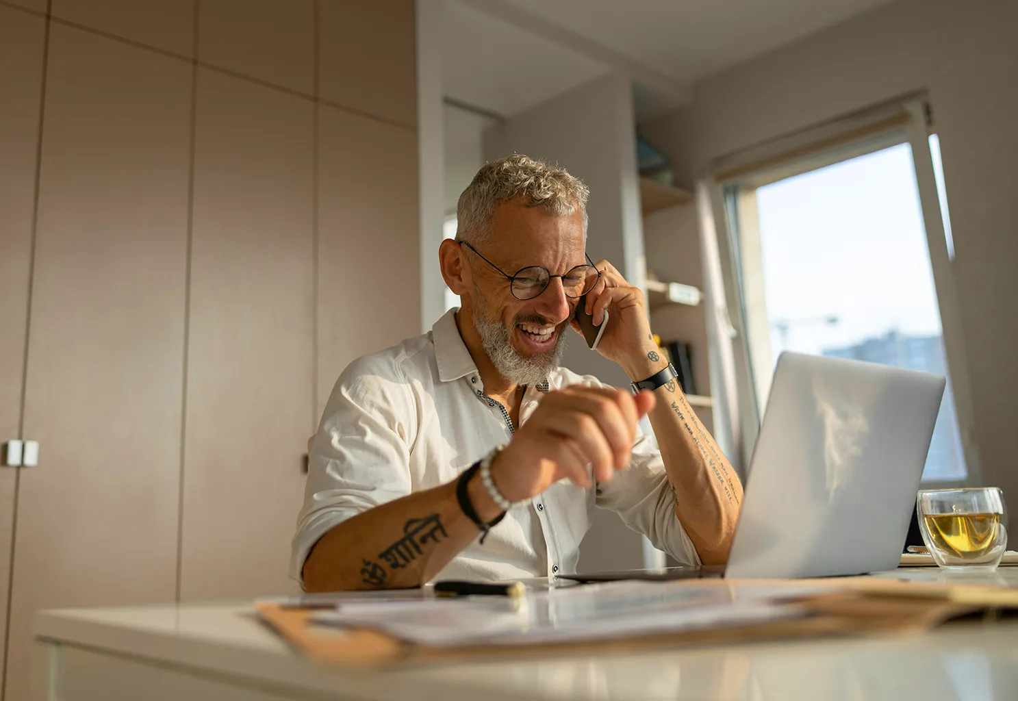 A man smiles while sitting at his desk talking on a phone. If he was once an overwhelmed entrepreneur, you'd never know it now.