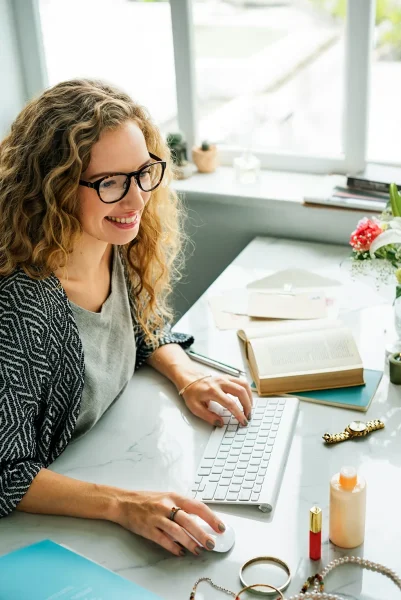 A smiling woman sits at her desk typing on a keyboard. If she was previously dealing with entrepreneur burnout, you'd never know it now.