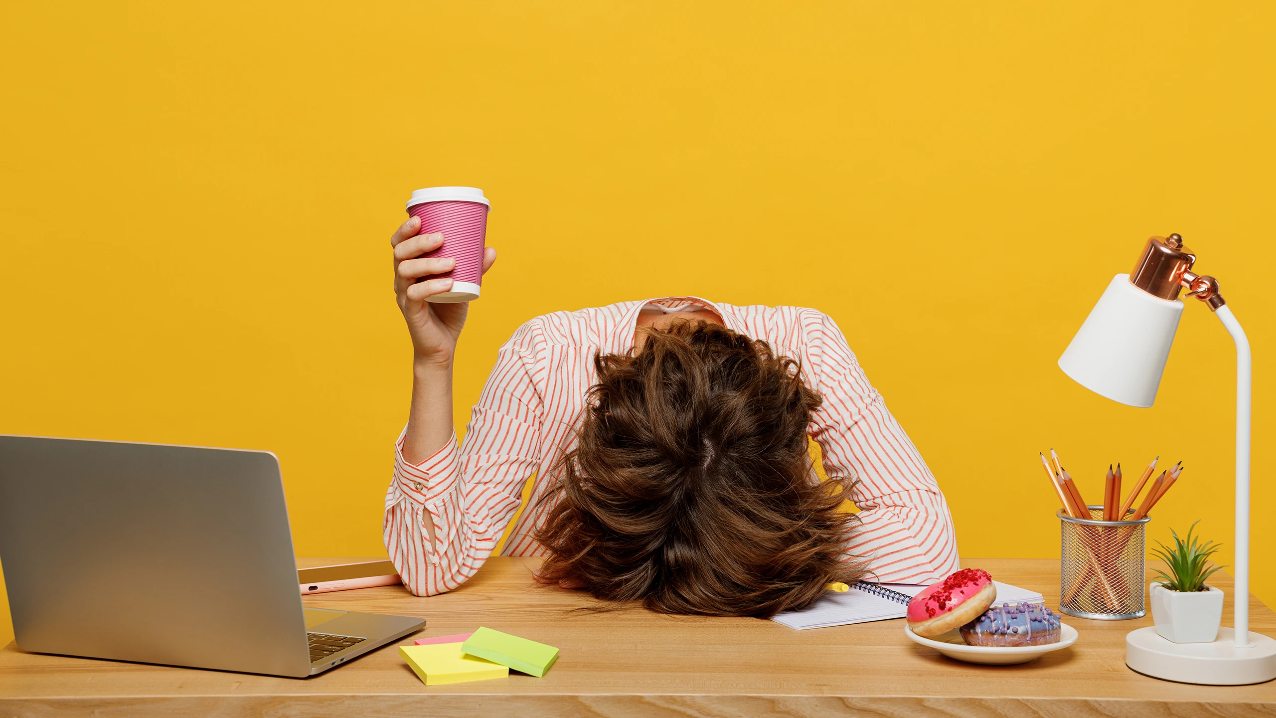 A frustrated person rests her head on her desk.